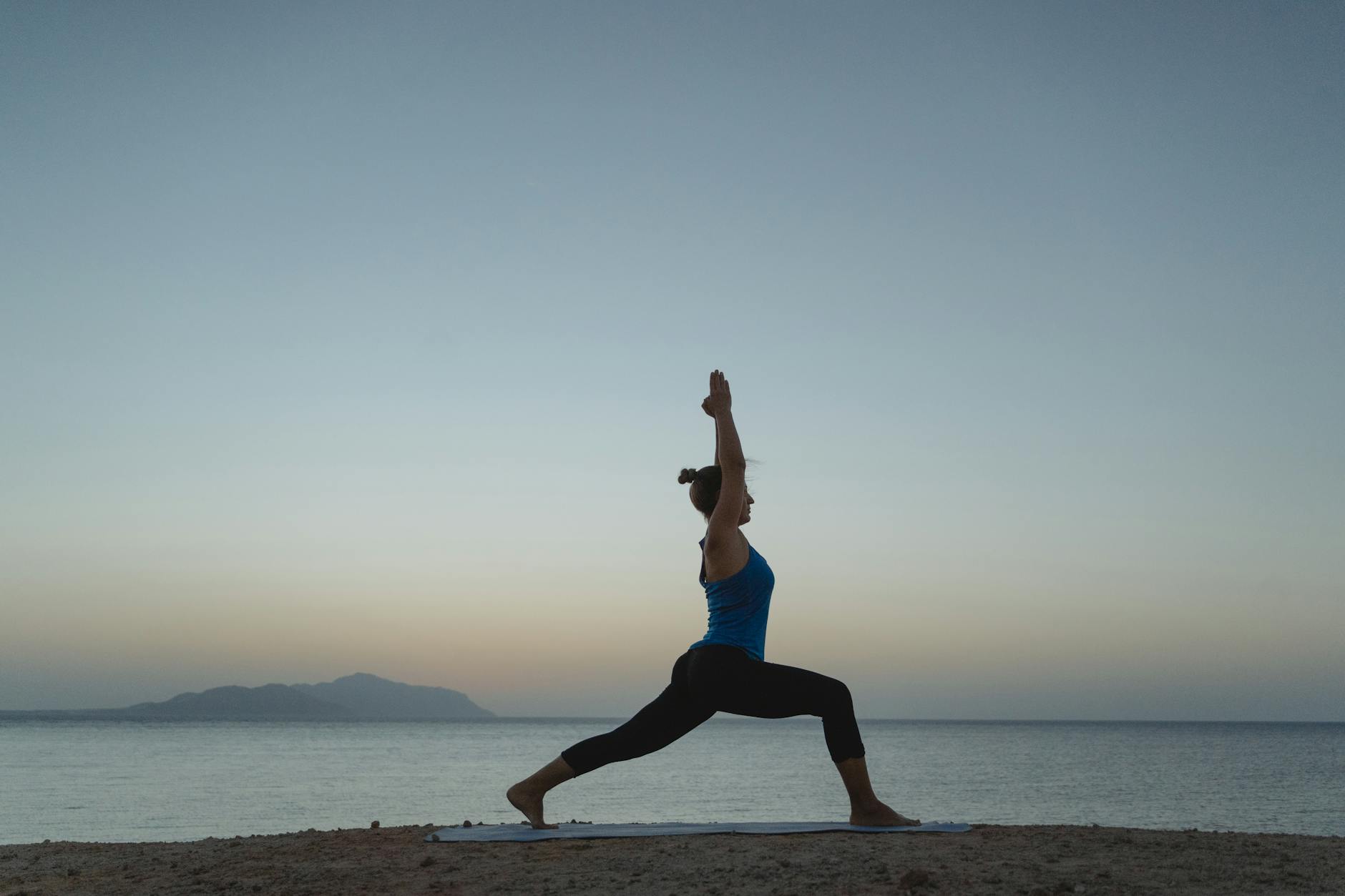 Woman in a peaceful warrior yoga pose outdoors.